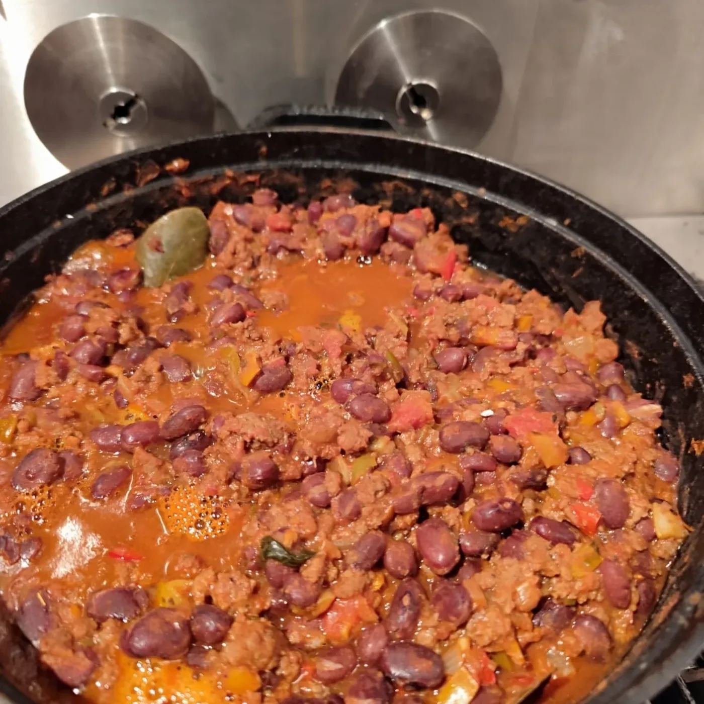 Feijoada apurando em panela grande sobre a churrasqueira